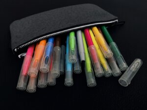 A group of pens sitting in front of a black bag